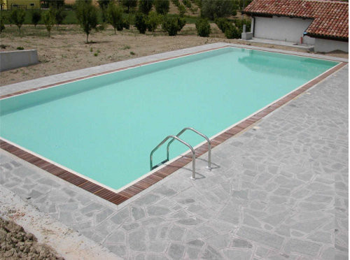 piscina a sfioro con canale perimetrale e griglia in legno di IPE